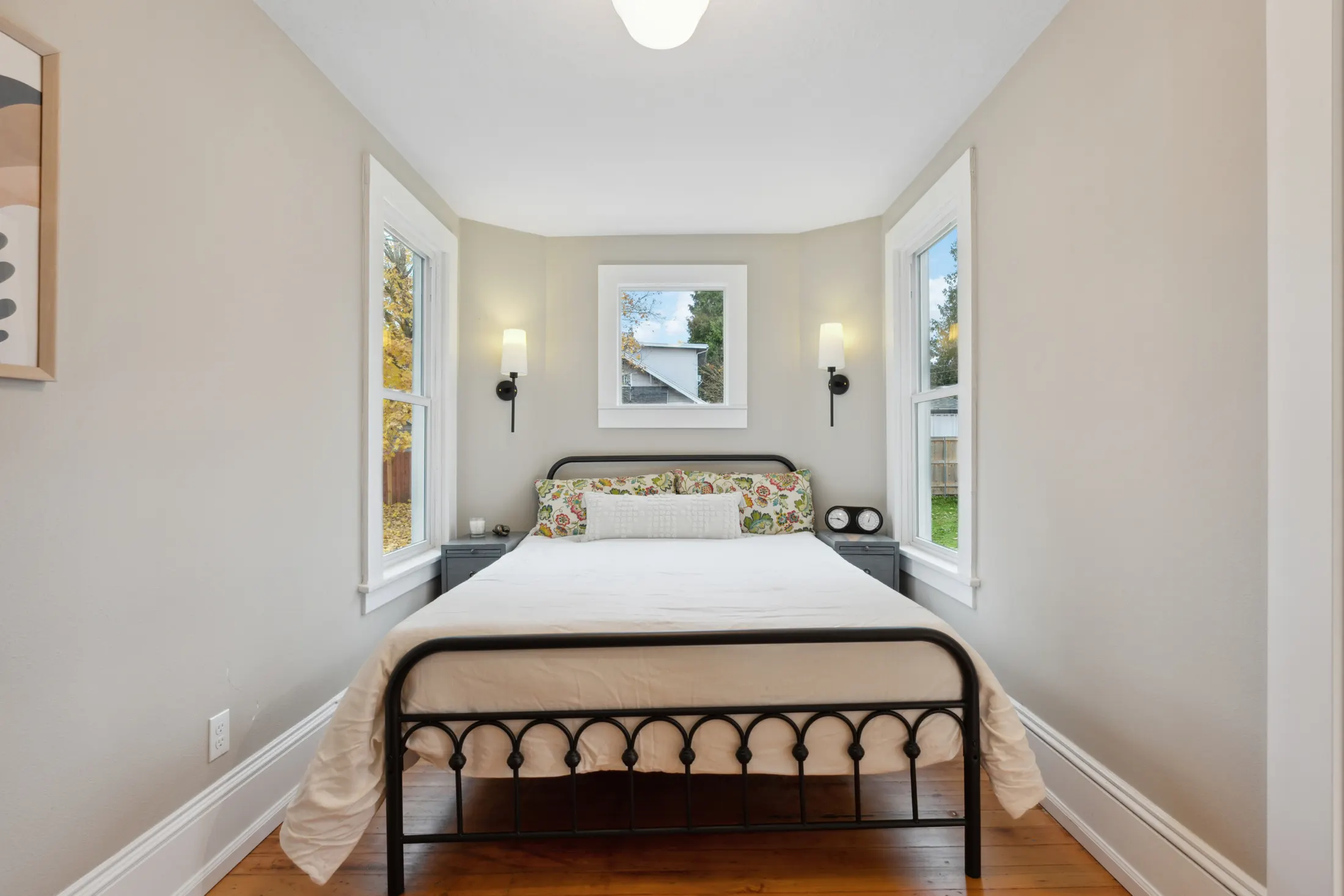 Bright bedroom with three windows and refinished hardwood floors by CRM Services