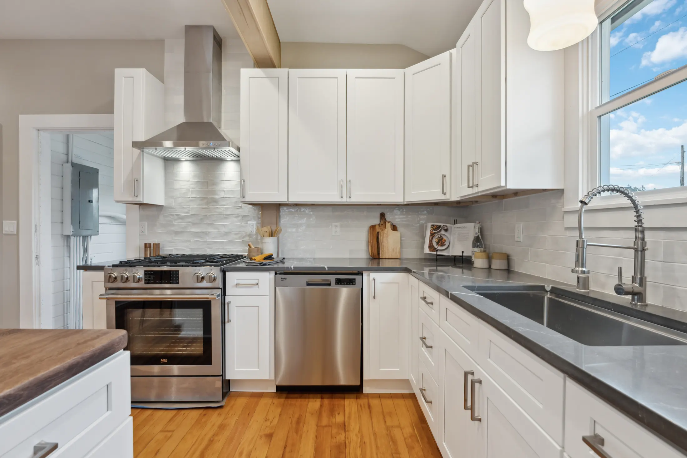 Remodeled kitchen with white shaker cabinets, stainless appliances, and quartz counters by CRM Services