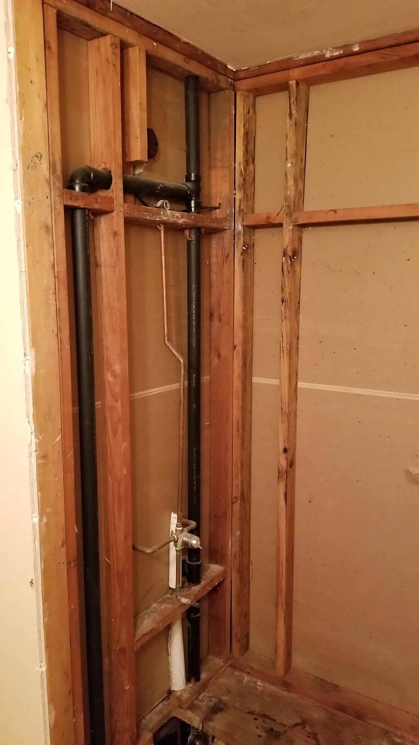 Tub wall stripped; drain and vent lines exposed.