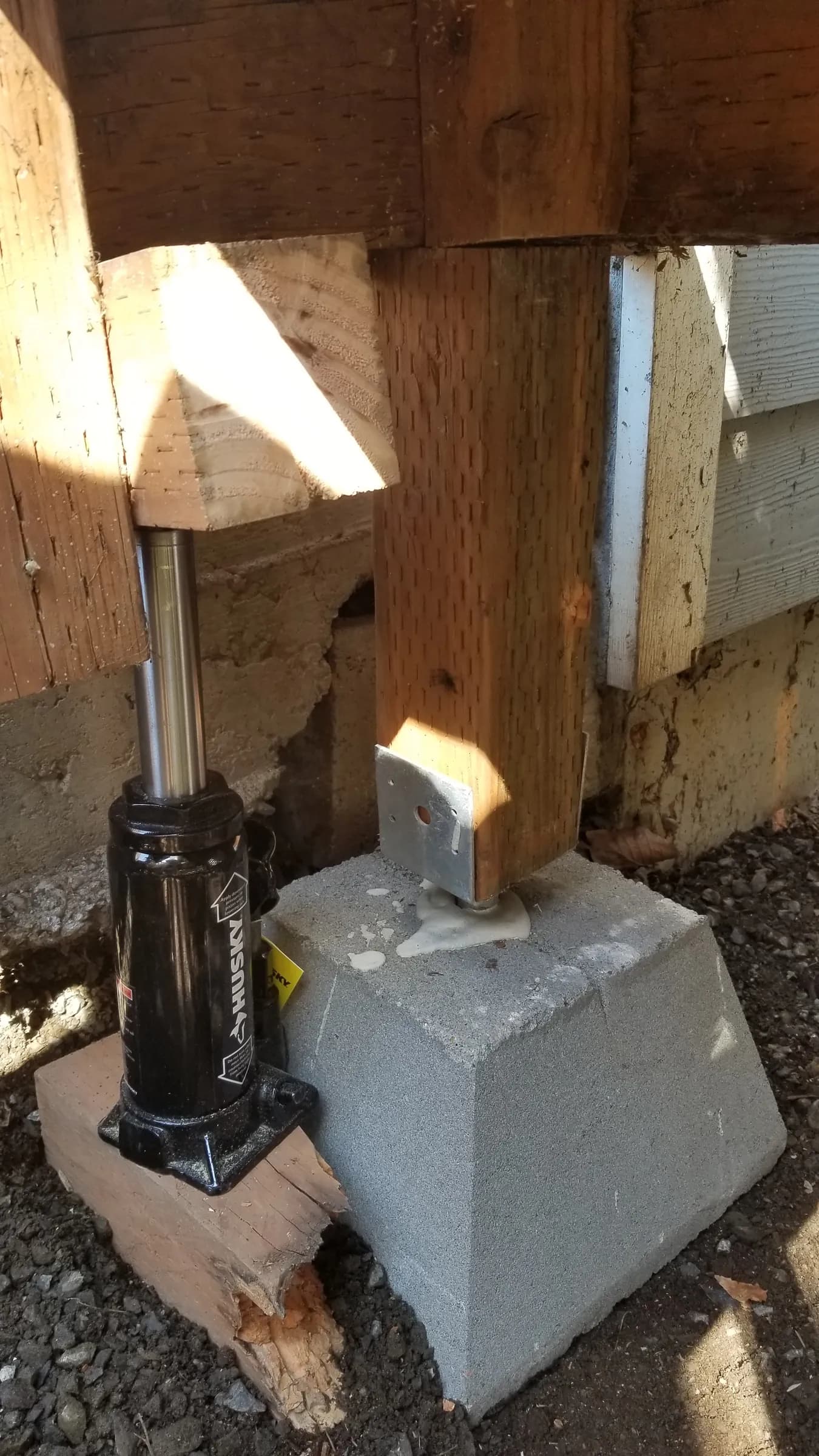 Repair: Deck post jacked up — the rotted post replaced and set on a new concrete pier block with a metal post base.