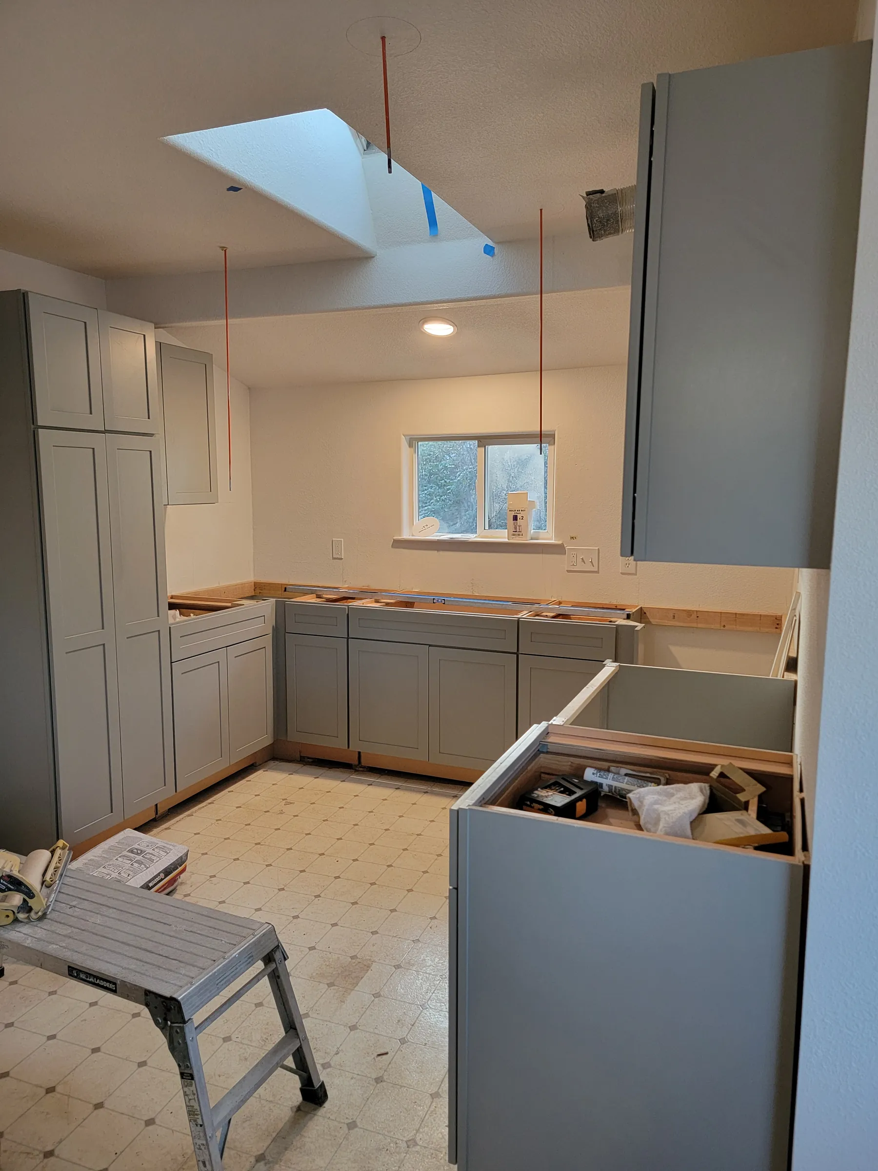 Install: Skylight in overhead; island base set and cabinets wrapping the room.