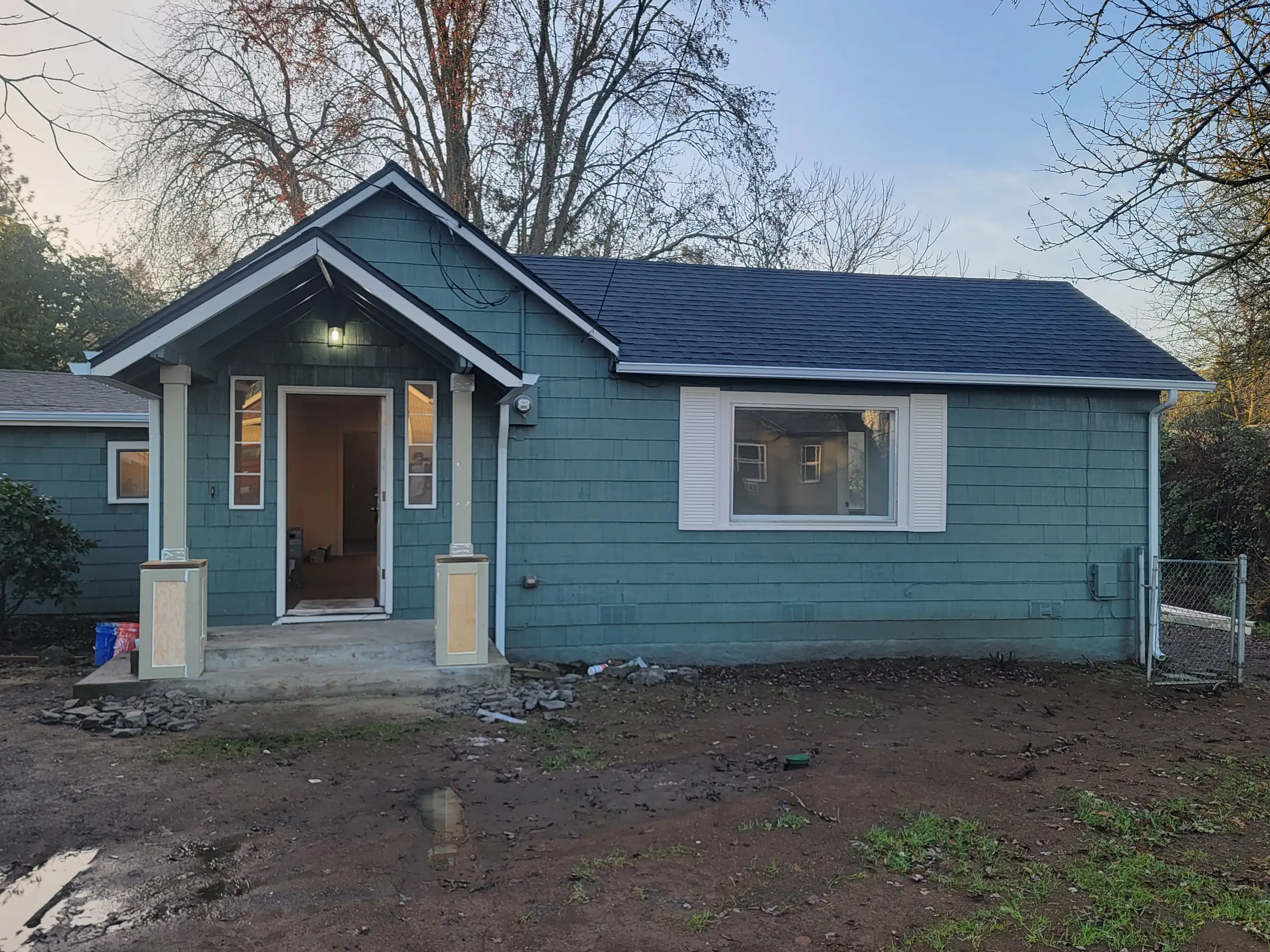Paint: Front elevation repainted with the new roof on; yard work still ahead.