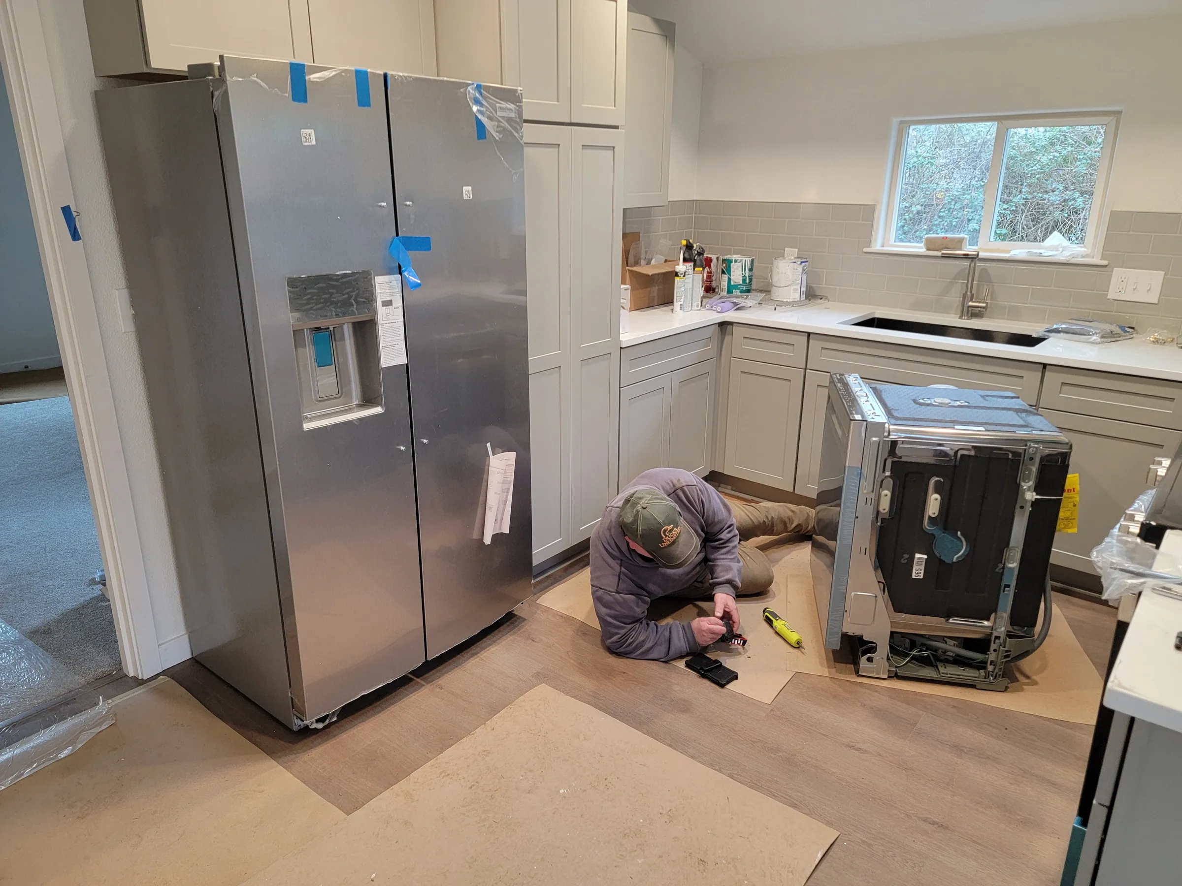 Install: Appliance install day — fridge unwrapped, dishwasher going in.