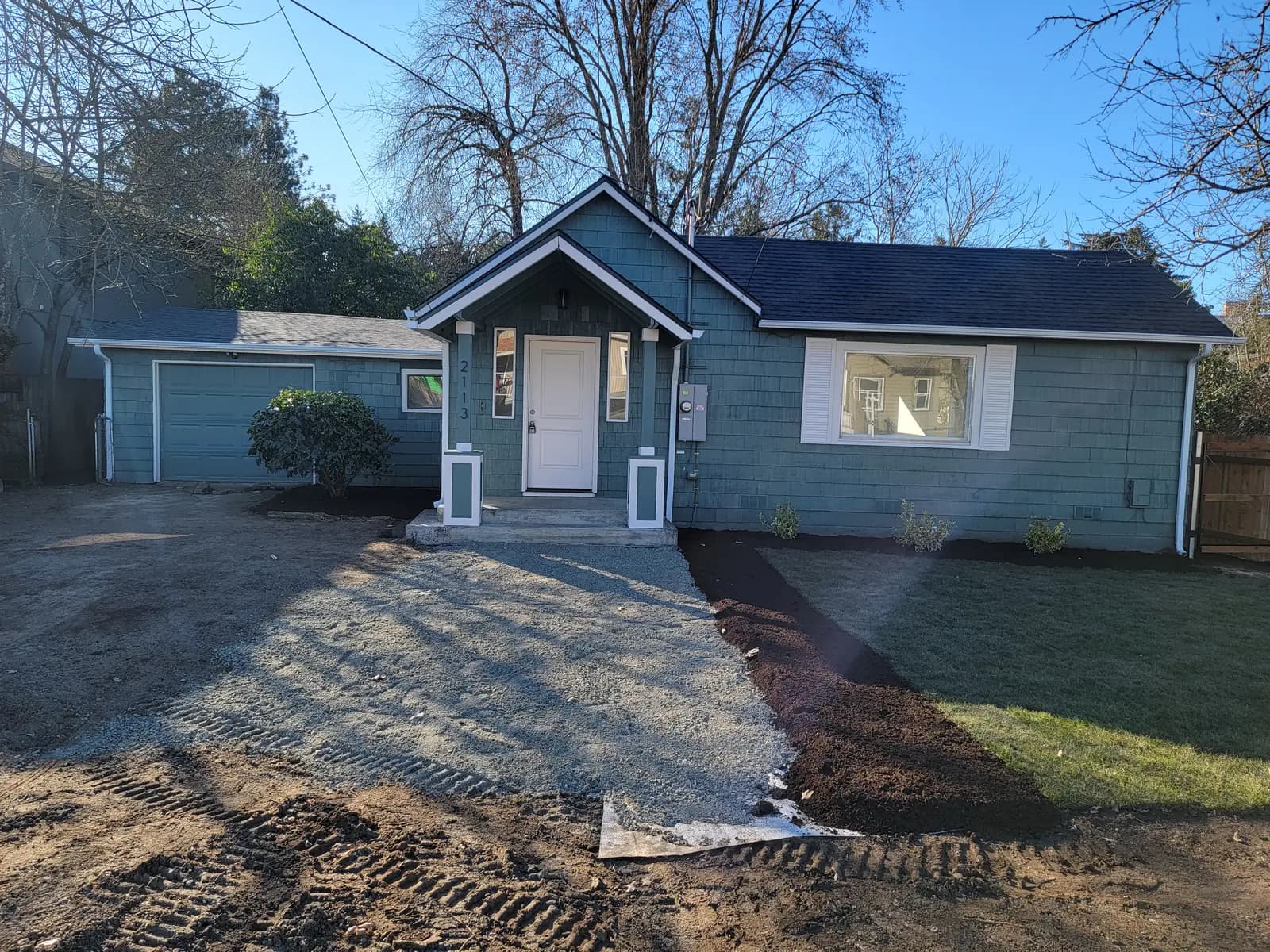 Done: Front exterior — gravel drive in and landscaping under way.