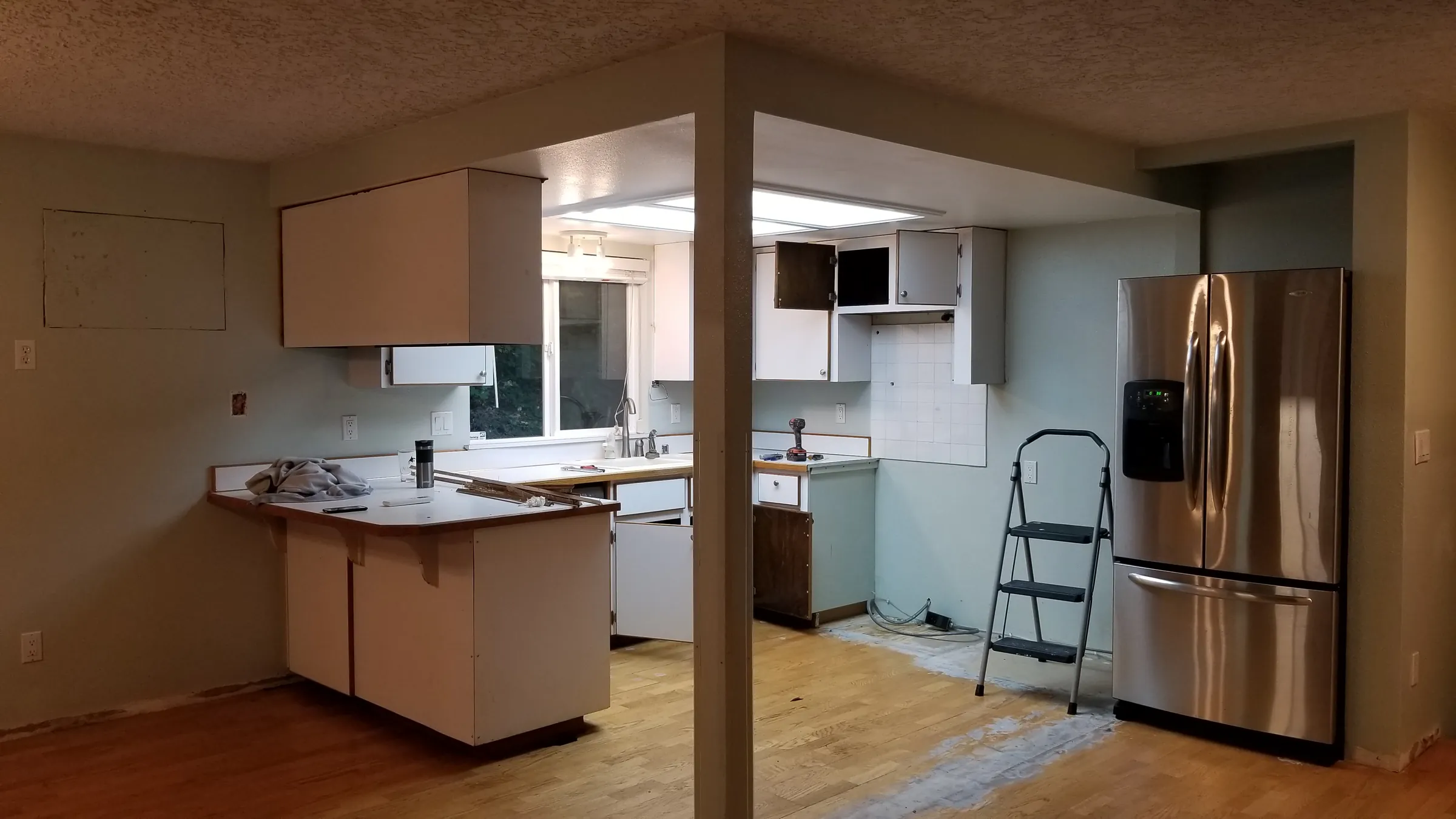 Before: The old kitchen before demo — white cabinets, island, wood floors.