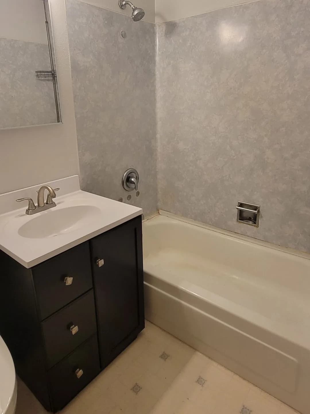 Before: NE 12th St bathroom remodel — dated tub surround replaced with a tiled walk-in shower, rain head and lit niche