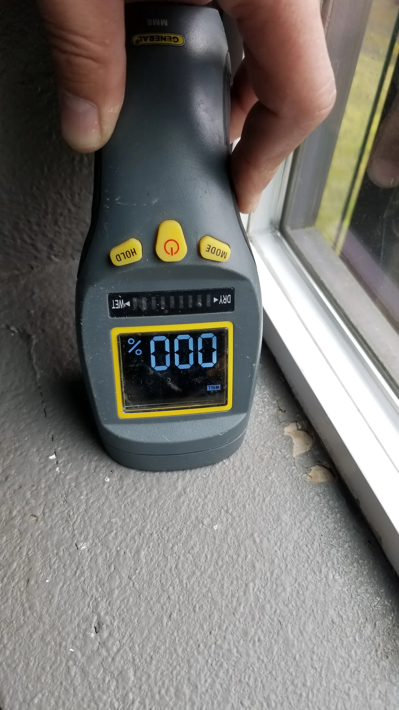 Before: Moisture meter check at the window sill — reading dry.